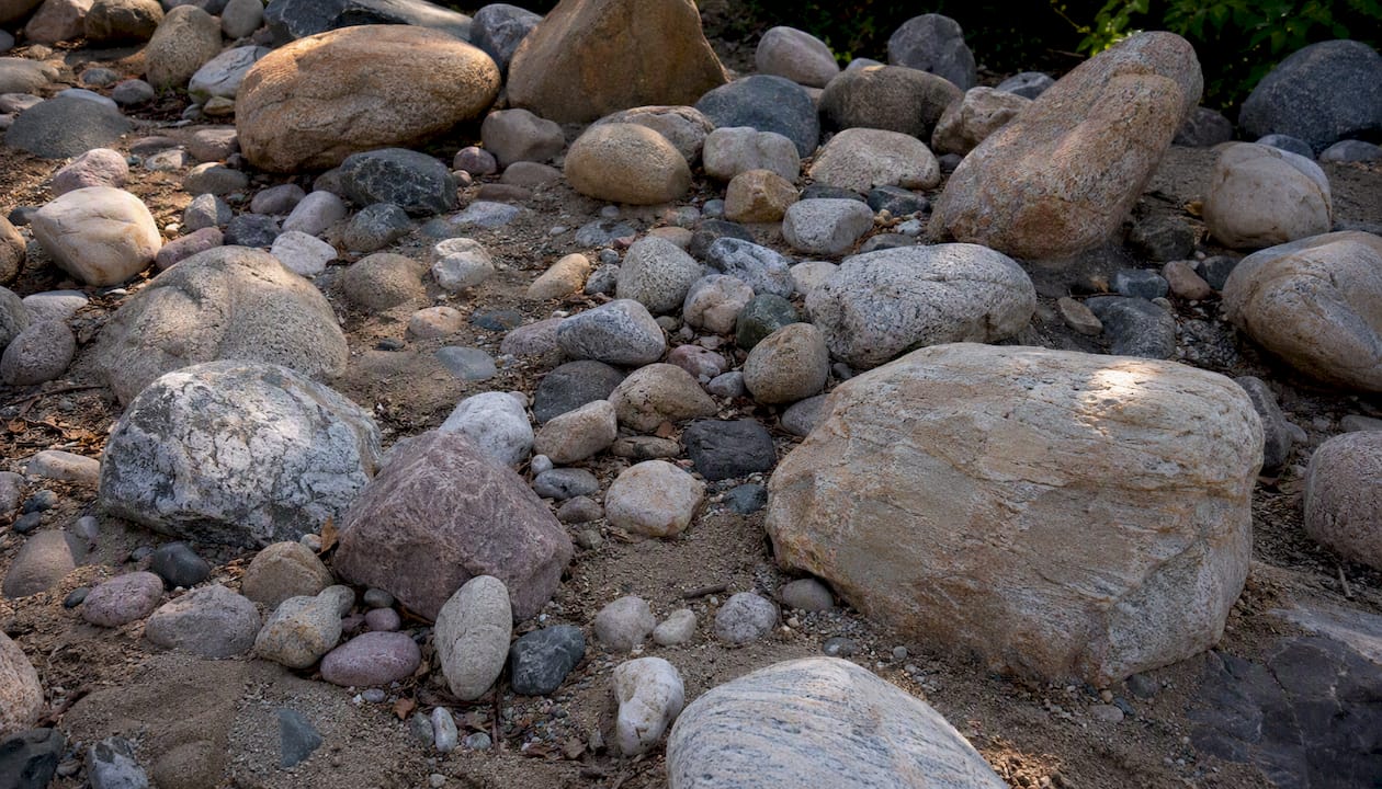 Close-up of different river rock sizes on soil