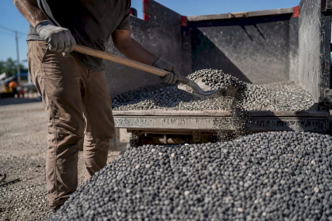 Worker shoveling gravel into truck bed