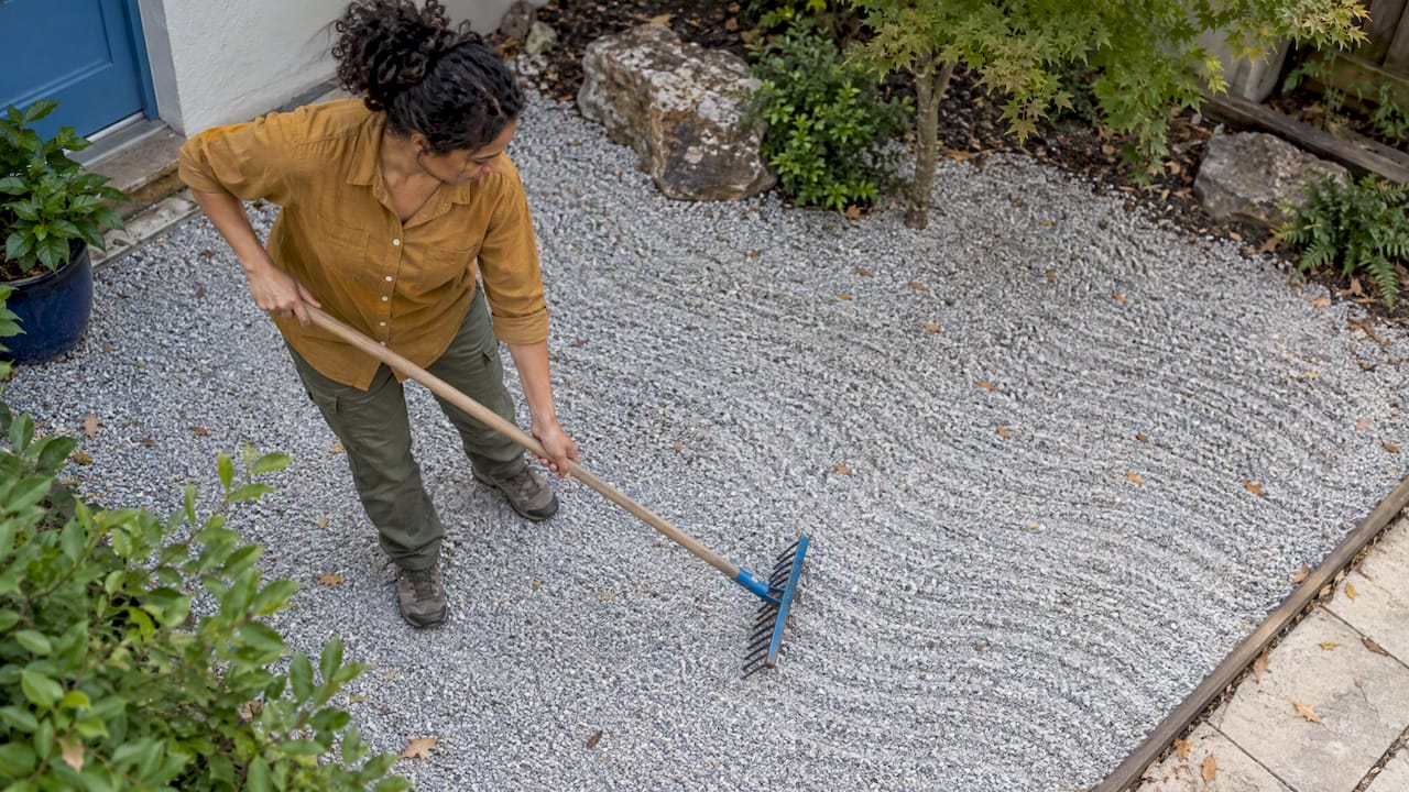 Gardener raking wave patterns into crushed granite